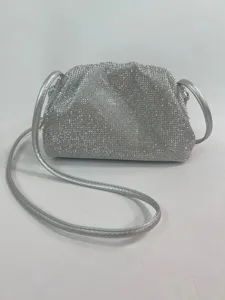 Close-up detail of silver rhinestone pleated cloud bag, evening clutch texture and strap design.