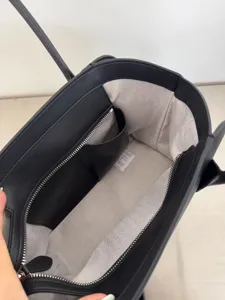Detailed view of black leather tote bag interior with herringbone lining and zipper pocket.