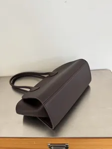 Detailed view of the dark brown leather tote bag, showing the bottom structure and handles.