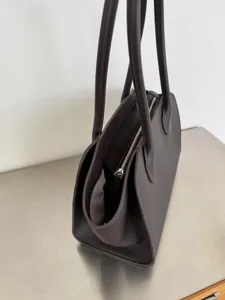 Detailed close-up shot of dark purple leather tote bag zipper and dual shoulder straps.