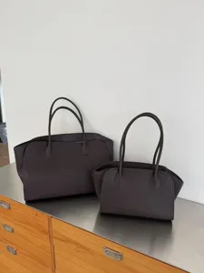 Detailed view of minimal cowhide tote bags in different sizes on a metal cabinet.