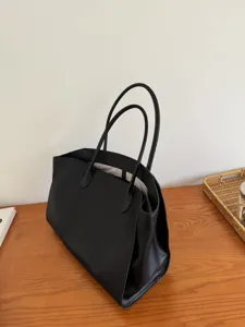 Black leather tote bag detail view, minimalist large capacity commuter shoulder bag for women.