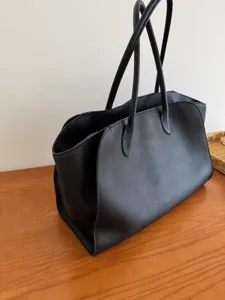 Detailed view of black leather tote bag, minimalist chic design with sturdy handles, daily chic.