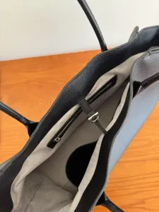 Detail view of black leather tote bag interior with chevron lining and secure strap closure.