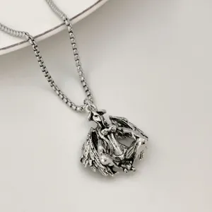 Close-up of vintage silver demon winged pendant necklace, detailed gothic jewelry design.
