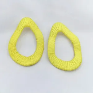 Detailansicht der leuchtend gelben umwickelten geometrischen abstrakten Mode Ohrringe Accessoire.