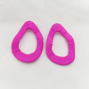 Nahaufnahme der pinken fadenummantelten geometrischen Ohrringe mit feiner Textur und Formdetail.