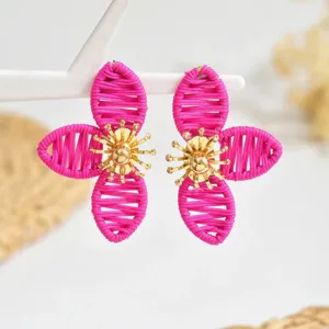Nahaufnahme der eleganten rosa geflochtenen Blumenohrringe mit goldenem Metall-Stempelkern.