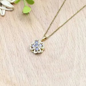 Nahaufnahme einer goldenen drehbaren vierblättrigen Kleeblatt-Halskette mit lila Zirkonia.