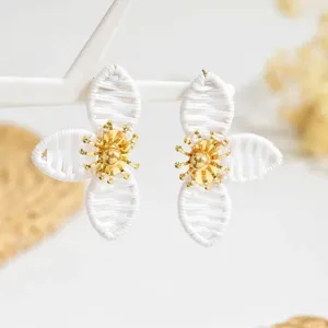 Elegante weiße geflochtene Blumenohrringe mit Goldmitte, schicker botanischer Schmuck.