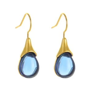 Close-up detail of elegant gold-plated teardrop blue crystal earrings, delicate droplet design.