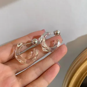 Close-up of clear irregular geometric resin hoop earrings with silver-tone ball back design.