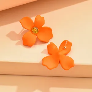 Orange four-petal flower stud earrings detail, vibrant gemstone accent, minimalist floral jewelry.