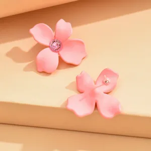 Pink flower stud earrings with sparkling center crystal, cute minimalist jewelry detail shot.