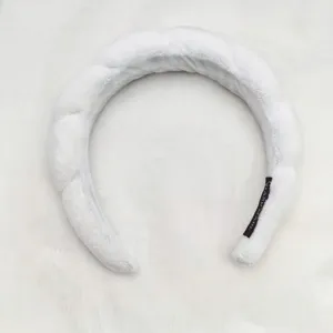Close-up detail of the white plush braided sponge headband showing soft fabric and inner tag.