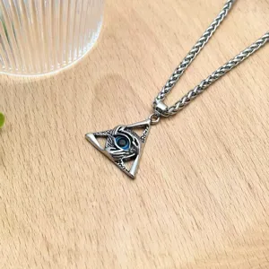 Detail view of the stylish devil eye triangular pendant necklace with wheat chain on wooden table.