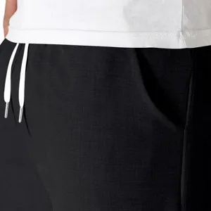 Primer plano del detalle de los pantalones cortos negros con textura tejida y cordón blanco.