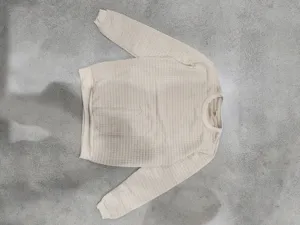 Close-up detail of the beige jacquard grid long-sleeve sweater, showing fine texture and knit.
