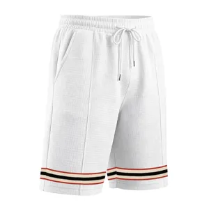 Close-up details of men's white waffle knit shorts with drawstring and striped hem.