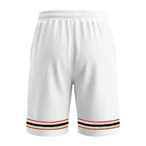 Detail shot of white waffle sports shorts featuring contrast color striped hem and elastic waist.
