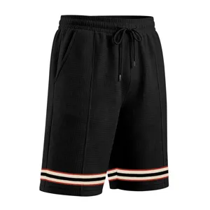 Close-up detail of men's loose waffle knit sports shorts with contrast striped hem.