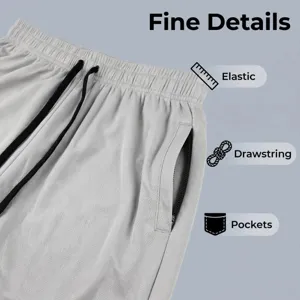 Close-up detail of grey athletic shorts showing elastic waistband, drawstring, and zipper pockets.