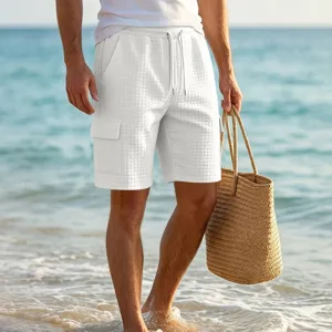 Detailed view of men white textured cargo shorts with pockets on a beach background scene.