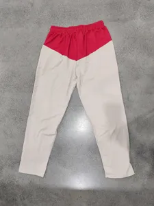 Detail shot of casual color-block straight leg trousers with red and white contrast design.