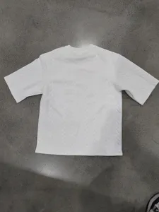 Detailed shot of white knit textured short sleeve crewneck t-shirt, high street casual style.