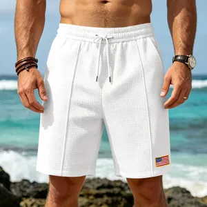 Close-up detail of mens white waffle knit beach shorts featuring flag patch design.
