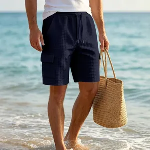 Detailed view of men's navy blue textured cargo shorts with drawstring waist at the beach.