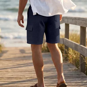 Detailed view of men's summer waffle cargo shorts, loose fit casual beach wear, dark blue.