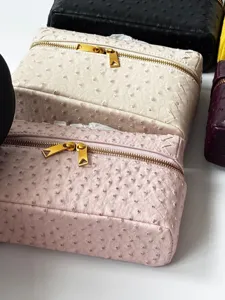 Neceser de piel con patrón de avestruz vanity case con detalles trenzados y cremallera.