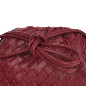 Woven leather handbag detail close-up showcasing intricate knot handle and texture.