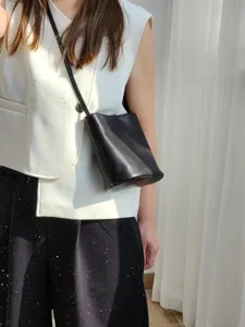 Vue détaillée du sac seau en cuir noir porté par le modèle, montrant un style décontracté.