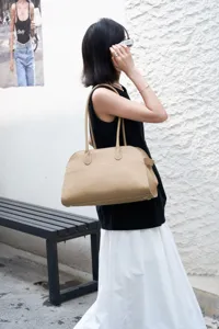 Close-up detail of beige pebbled leather tote bag with long handles and elegant style.