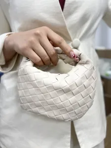Detailed view of women woven leather handbag, minimalist solid color short handle design fashion bag.