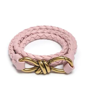 Nahaufnahme des eleganten rosa geflochtenen Ledergürtels mit stilvoller Metallknotenschnalle.