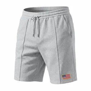 Men grey waffle knit casual sports shorts with adjustable drawstring and flag patch detail.