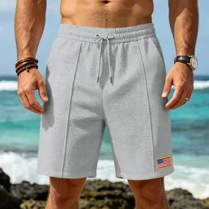 Close-up detail of men's casual waffle knit shorts, showing elastic drawstring waist and patch.