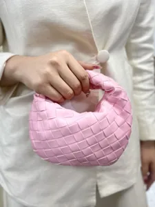 Pink woven leather handbag detail showing exquisite braided texture and compact artisan craftsmanship.