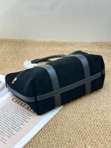 Detalle del bolso tote de ante negro, bolso de lujo con detalles de correas de cuero.