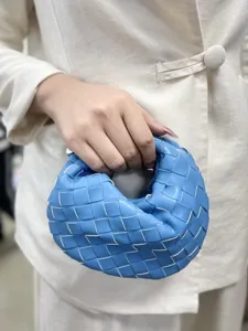Detailed shot of the blue woven leather handbag held in hand, showing fine texture and style.