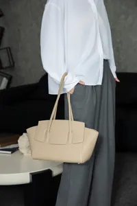 Close-up view of a minimalist beige leather tote bag featuring elegant design and fine texture.
