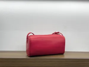 Red leather cylindrical bag detail, soft texture and compact design for daily wear.