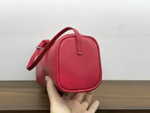 Red leather cylinder bag detail view, minimalist top layer cowhide shoulder handbag.