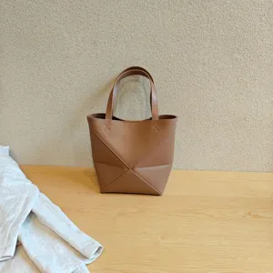 Détail de sac cabas géométrique repliable en cuir marron avec une structure unique.