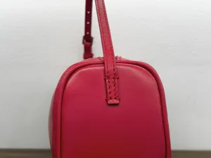 Minimalist red leather 90s shoulder bag detail shot showing exquisite stitching craftsmanship.