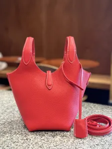 Red leather bucket bag close-up showing premium texture and white stitching details.