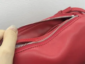 Red leather bag zipper detail showcasing premium texture and smooth metal hardware finish.